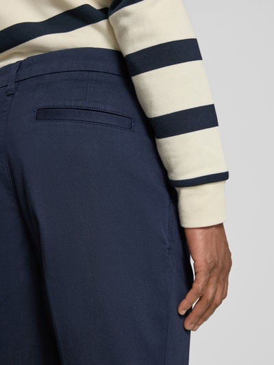 Männermodel trägt Regular Fit Chino aus Baumwoll-Mix Modell 'TAAMIR PLEATED' von Armedangels in Uni-Optik, Nahaufnahme Rückansicht.