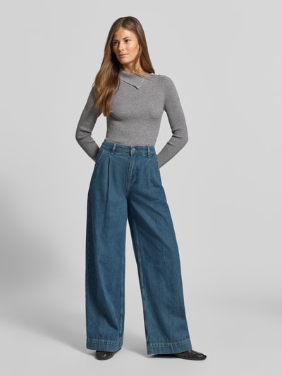 Frauenmodel trägt Wide Fit Jeans mit gelegten Falten von MYON aus reiner Baumwolle in Blau, mit Seiten- und Gesäßtaschen, Ganzkörperansicht von vorne.