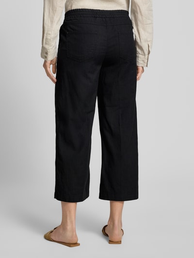 Frauenmodel trägt Culotte mit französischen Eingrifftaschen Modell 'Linn' von Angels, Reine Baumwolle, Loose-Fit, Elastischer Bund, Gesäßtaschen, Schwarz, lockerer Schnitt, glatte Textur, Ganzkörperansicht Rückansicht.