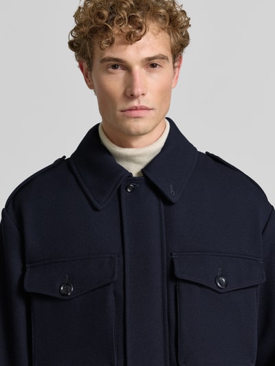 Männermodel trägt Jacke aus Viskose-Mix von Emporio Armani in Dunkelblau mit Umlegekragen und Brusttaschen, Nahaufnahme Oberkörper.