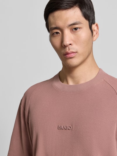 Männermodel trägt Regular Fit T-Shirt aus reiner Baumwolle Modell 'DAFFL' von HUGO, unifarben, strukturierte Jacquard-Optik, Nahaufnahme Oberkörper.