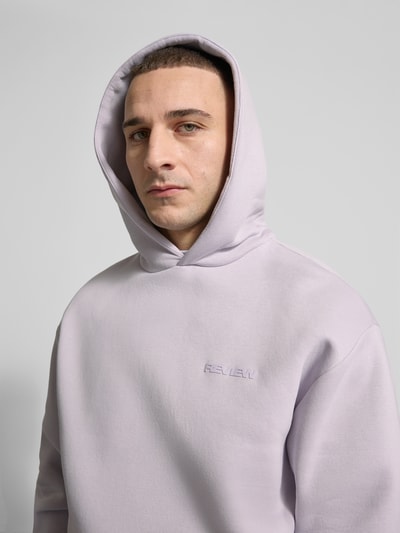 Männermodel trägt Hoodie mit Känguru-Tasche von REVIEW in hellem Lila, Baumwollmischung, lockere Passform, Nahaufnahme Oberkörper.