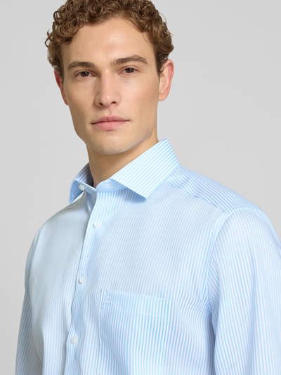 Męski model nosi Modern Fit Business-Hemd aus Baumwolle mit Kentkragen od OLYMP, błękitny w delikatne paski, czysta bawełna, krój modern fit, kołnierzyk kent, zapięcie na guziki, długość tyłu w rozmiarze 40: 80 cm, szerokość ramion w rozmiarze 40: 46 cm, długość rękawa w rozmiarze 40: 66 cm, zbliżenie na górną część ciała.