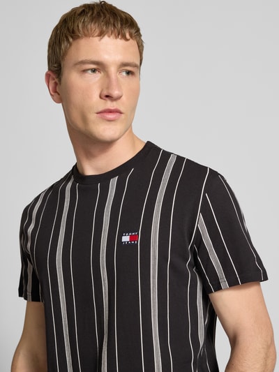 Männermodel trägt Regular Fit T-Shirt aus reiner Baumwolle von Tommy Jeans mit Optik:Allover-Muster, Label-Stitching-Applikation, Rundhals, Kurzarm; Nahaufnahme Oberkörper.