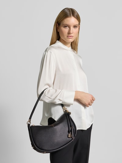 Kobiece model prezentuje Handtasche mit Label-Applikation od Guess, czarna torebka półokrągła, srebrne detale, Szerokość w rozmiarze 1: 30 cm, długość: 19 cm, głębokość: 9 cm, długość paska na ramię: 50 cm, zdjęcie w ujęciu całej sylwetki z przodu.