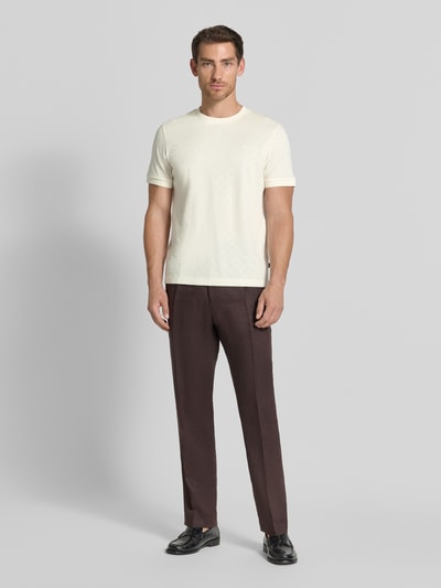 Männermodel trägt T-Shirt mit Logo-Stitching Modell 'Benluco' von JOOP!, cremefarben, Strukturmuster, Rundhals, Ganzkörperansicht von vorne, Regular Fit, reine Baumwolle, Rückenlänge 65 cm bei Größe M.