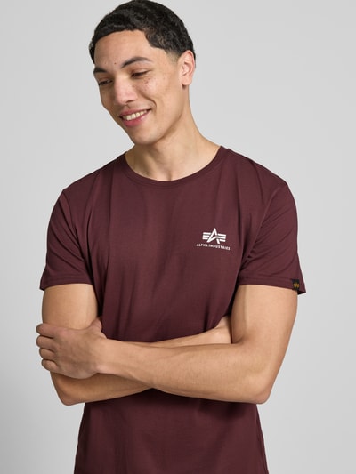 Männermodel trägt T-shirt mit Label-Details Modell 'BASIC' van Alpha Industries aus puur katoen, recht model, ronde hals, ruglengte maat M 67 cm, nahaufnahme bovenlichaam.