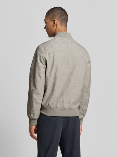 Männermodel trägt Bomberjacke mit Pattentaschen und Reißverschluss von PAUL SMITH, Loose-Fit, Stehkragen, graue Struktur, Ganzkörperansicht Rückansicht. Rückenlänge bei Größe M: 65 cm, Schulterbreite: 44 cm, Brustweite: 53 cm, Ärmellänge: 67 cm, gerippte Abschlüsse.