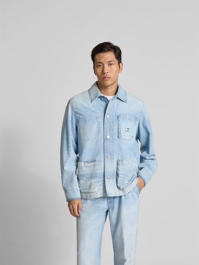 Männermodel trägt Relaxed Fit Hemdjacke in Denim-Optik von Closed, Reine Baumwolle, Aufgesetzte Taschen, durchgängige Knopfleiste, hellblau, Ganzkörperansicht von vorne.