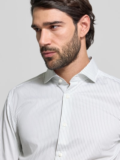 Männermodel trägt Slim Fit Businesshemd aus Baumwoll-Mix Modell 'HANK' von BOSS, gestreiftes Muster, Nahaufnahme Oberkörper.
