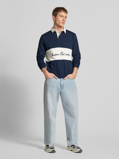 Männermodel trägt Regular Fit Langarm-Poloshirt mit Label-Stitching von REVIEW, Reine Baumwolle, Kontraststreifen, Ganzkörperansicht von vorne.