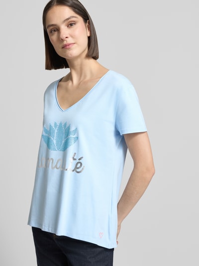 Frauenmodel trägt Damen T-Shirt mit Ziersteinbesatz Modell 'Namaste' von miss goodlife, hellblau, Baumwoll-Elasthan-Mix, Regular-Fit, V-Ausschnitt, Rückenlänge bei Größe S 67 cm, Ganzkörperansicht von vorne.
