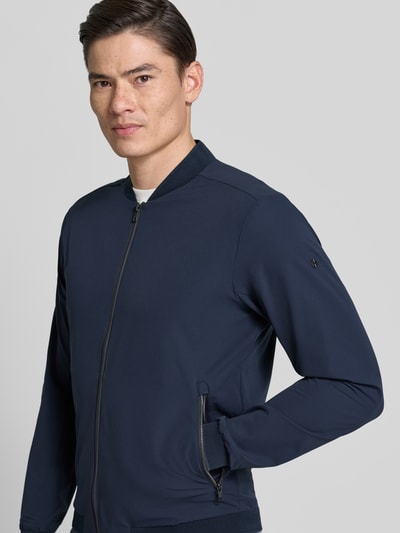 Männermodel trägt Regular Fit Jacke mit Stehkragen Modell 'Campo' von SCANDINAVIAN EDITION in Dunkelblau, Zweiwege-Reißverschluss, Eingrifftaschen, elastische Abschlüsse, Textur glatt, Ganzkörperansicht von vorne, Rückenlänge bei Größe M 67 cm, Schulterbreite 44 cm, Brustweite 51 cm, Ärmellänge 64 cm.