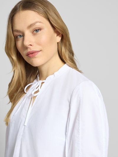 Modelka nosi Bluse mit Serafino-Ausschnitt und Keulenarm von Christian Berg Woman Selection, biała bawełna, krój loose fit, zbliżenie na górną część ciała