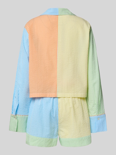 Frauenmodel trägt Comfort Fit Pyjama aus reiner Baumwolle Modell 'SCALLOP SEERSUCKER' von Polo Ralph Lauren, wzór w paski, komplet, faktura tkaniny seersucker, żółto-niebiesko-pomarańczowo-zielony kolor, długość krótka, wyhaftowane logo, kołnierz z połami, dekolt w serek, zapięcie: listwa guzikowa, rękaw: długi rękaw, zakończenie rękawów: mankiet, zakończenie: elastyczny pas, bluzka z kieszenią na piersi i wpuszczanymi kieszeniami, wykończenie materiału: marszczenie, materiał: czysta bawełna, komplet dwuczęściowy, widok z tyłu w całej sylwetce.