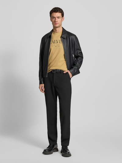 Männermodel trägt T-Shirt mit Label-Print und Rundhalsausschnitt von CK Calvin Klein in Beige, Regular-Fit, Reine Baumwolle, Ganzkörperansicht von vorne.