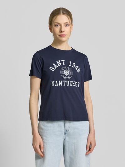 Frauenmodel trägt T-Shirt mit Label-Print von GANT in Dunkelblau, Baumwolle, Regular Fit, Rundhalsausschnitt, Ganzkörperansicht von vorne.