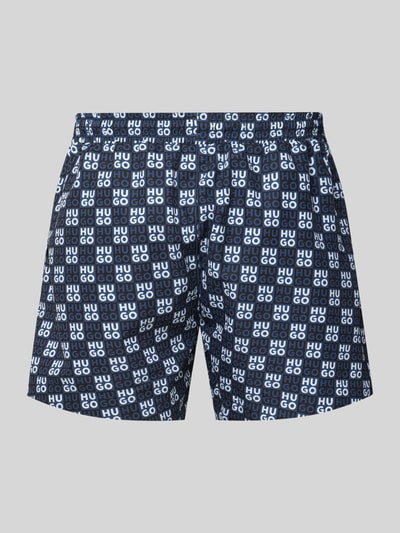 Produktfoto, Regular Fit Badeshorts mit Label-Prägung Modell 'AARON' von HUGO, Optik: Unifarben, Passform: Regular-Fit, Applikation: Label-Print, Bundabschluss: Elastisch mit Tunnelzug, Taschen: Seitliche Eingrifftaschen, überwiegend Blautöne mit weißem HUGO-Schriftzug auf glatter Textur.