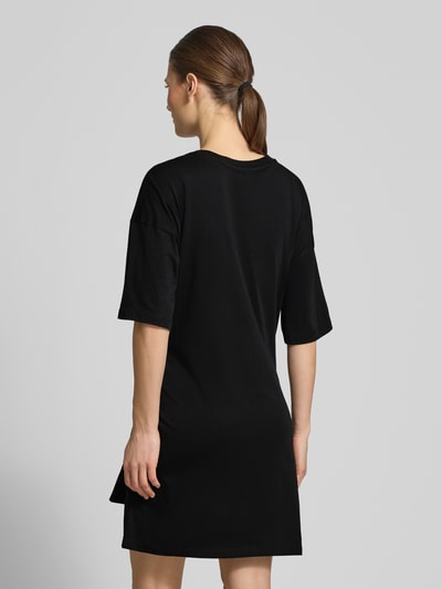 Modelka nosi T-Shirt-Kleid mit Rundhalsausschnitt und 1/2-Arm od ARMANI EXCHANGE, czarna bawełna, prosty krój, długość mini, detal z logo, szerokość w rozmiarze S: 50 cm, długość tyłu: 82 cm, długość rękawa: 31 cm, widok całej sylwetki z tyłu
