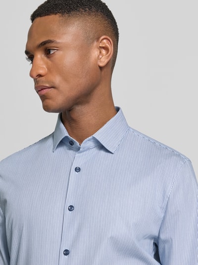 Mannenmodel draagt Super Slim Fit Business-Hemd met Kentkraag van OLYMP No. Six, fijne blauwe strepen, katoenmix met stretch, knopenlijst, close-up bovenlichaam.