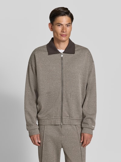 Männermodel trägt Jacke aus Baumwoll-Mix Modell 'Arelio' von DRYKORN in beige-grau mit Zwei-Wege-Reißverschluss, lockerem Schnitt, Nahaufnahme Oberkörper. Rückenlänge 72 cm, Ärmellänge 62 cm, seitliche Eingrifftaschen, überschnittene Schultern.