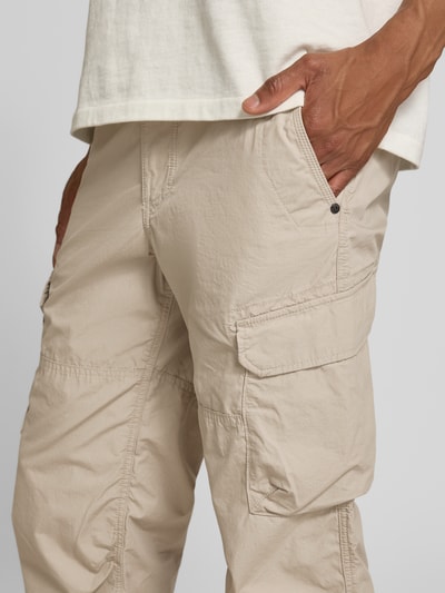 Mężczyzna nosi Capri-Bermudas mit Cargotaschen von camel active, beżowa bawełna, krój regular fit, kieszenie cargo, detal z logo, zbliżenie na biodra