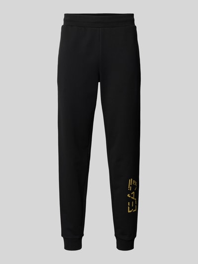 Produktfoto, czarne spodnie dresowe z elastycznym pasem i nadrukiem z logo EA7 Emporio Armani, bawełna, krój regular fit, długość wewnętrzna nogawki 78 cm dla rozmiaru M