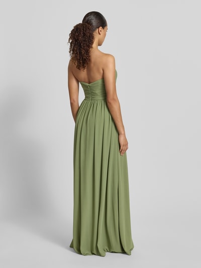Frauenmodel trägt Maxikleid im Off-Shoulder-Look von Mascara aus grünem Chiffon mit Taillierter Schnitt, Reißverschluss hinten, Ganzkörperansicht Rückansicht. Rückenlänge 125 cm, Brustweite 31 cm bei Größe 36.
