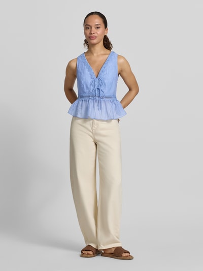 Frauenmodel trägt Top aus Lyocell-Mix mit Zierschleifen Modell 'Elena' von Mango, blau, taillierte Passform, V-Ausschnitt, Ganzkörperansicht von vorne.