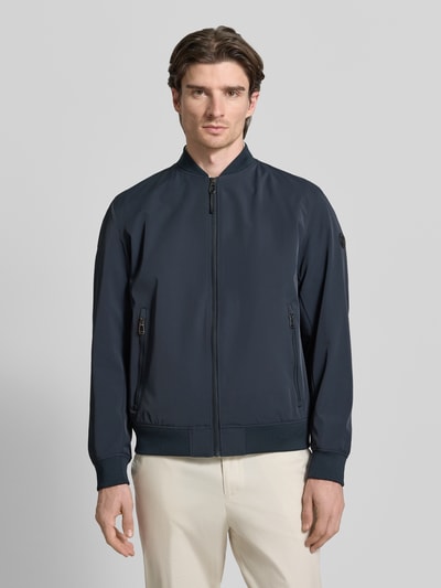 Männermodel trägt Regular Fit Jacke mit Stehkragen Modell 'Carlos' von JOOP! Collection in Dunkelblau, Reißverschlusstaschen, Ganzkörperansicht von vorne.
