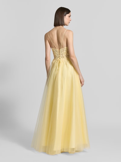 Modelka nosi Maxikleid aus Tüll mit rückseitiger Schnürung von Luxuar, żółty tiul, taliowany fason, sukienka gorsetowa, cienkie ramiączka, hafty, długość tyłu w rozmiarze 36: 145 cm, szerokość klatki piersiowej w rozmiarze 36: 33 cm, widok całej sylwetki od tyłu.