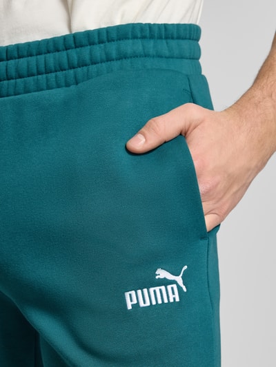 Männermodel trägt Sweatpants mit elastischem Bund von PUMA PERFORMANCE aus Baumwoll-Mix, Label-Stitching, Nahaufnahme Oberschenkel.