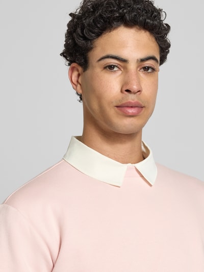 Mannelijk model draagt Regular Fit Sweatshirt uit katoenmix model 'CERES' van Only & Sons in effen lichtroze met ronde hals en label patch, sweatstof met geribde manchetten en zoom, materiaal katoenmix. Close-up bovenlichaam.