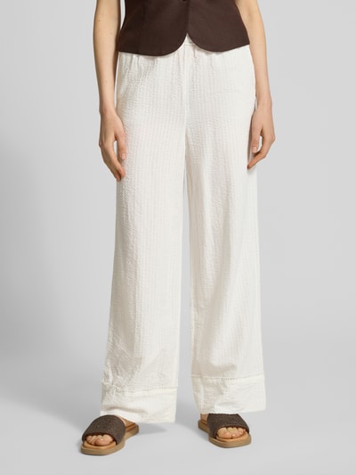 Frauenmodel trägt Relaxed Fit Weite Hose aus Baumwoll-Viskose-Mix von Tom Tailor Denim, Optik:Unifarben, Muster: Gestreift, Materialverarbeitung: Seersucker, seitliche Eingrifftaschen, Tunnelzug, Bundabschluss: Elastisch, Farbe: Weiß, Struktur: leicht gecrinkelt, Ganzkörperansicht von vorne.