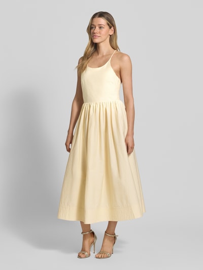 Frauenmodel trägt Midikleid mit Eingrifftaschen Modell 'COVER' von SUNCOO PARIS aus Baumwoll-Mix in A-Linie mit Spaghettiträgern, Rückseitige Schnürung, Ganzkörperansicht von vorne.