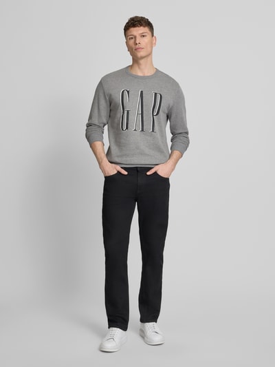 Mannenmodel draagt 'Sweatshirt mit Logo' van GAP in grijs katoenmix, regular fit, ronde hals, logoprint, ruglengte maat M 70 cm, mouwlengte 67 cm, geheel vooraanzicht.