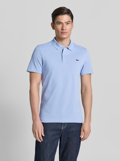 Männermodel trägt Regular Fit Poloshirt aus Baumwoll-Mix von Lacoste, Optik: Unifarben, Logo-Patch, Polokragen, Kurzarm, Ganzkörperansicht von vorne.