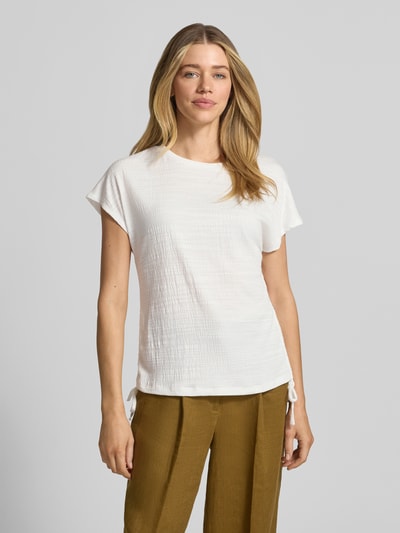 Modelka kobieca nosi Regular Fit T-Shirt mit Viskose-Anteil od Apricot, jasny kolor, strukturalny wzór, ozdobne kokardki, okrągły dekolt, elastyczna mieszanka materiałów, krój regular fit, długość tyłu w rozmiarze S: 59 cm, widok całej sylwetki z przodu.