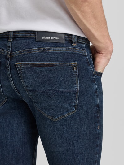 Männermodel trägt Jeans mit Eingrifftaschen Modell 'Dijon' von Pierre Cardin, mieszanka bawełny z dodatkiem streczu, krój slim fit, wpuszczane kieszenie, szerokość w rozmiarze 32/32: 39 cm, długość wewnętrzna nogawki 78 cm, ciemnoniebieski denim, widoczne szwy, detal tylnej kieszeni, zbliżenie na tył.
