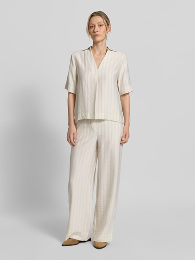 Frauenmodel trägt Regular Fit Hemdbluse aus Lyocell-Mix Modell 'MARIE' von Selected Femme, Optik:Allover-Muster mit Nadelstreifen, Kragenform: Johnny-Kragen, Rückenpasse mit Raffung, V-Ausschnitt, verdeckte Knopfleiste, Ärmelform: Kurzarm, in hellem, leicht glänzendem Stoff, Ganzkörperansicht von vorne.