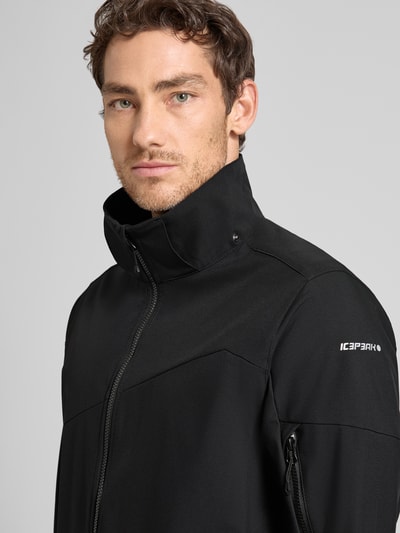 Männermodel trägt kurtka Regular Fit z kapturem model 'BARMSTEDT' od Icepeak, czarny kolor, zamek błyskawiczny, nadruk z logo, stójka, kieszeń na rękawie, wpuszczane kieszenie, długość tyłu w rozmiarze 50: 78 cm, szerokość ramion w rozmiarze 50: 43 cm, szerokość klatki piersiowej w rozmiarze 50: 54 cm, długość rękawów w rozmiarze 50: 71 cm, nahaufnahme górnej części ciała.