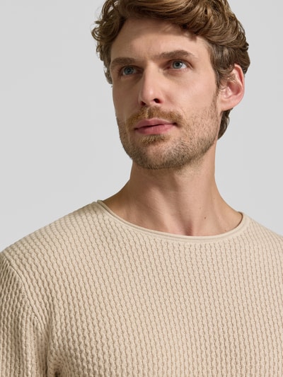Mannenmodel draagt gebreide pullover met structuurpatroon Model 'BLUMASON' van JACK & JONES, puur katoen, recht model, ronde hals, labelpatch, detailopname bovenlichaam.