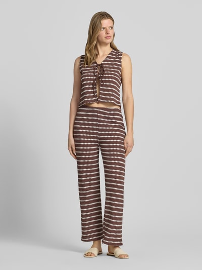 Frauenmodel trägt Loose Fit Stoffhose mit Baumwoll-Anteil Modell 'EVA LIFE' von Only mit Allover-Muster, braun-weiß, Stricktextur, Ganzkörperansicht von vorne.