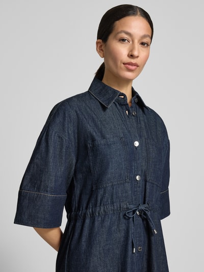 Frauenmodel trägt Knielanges Jeanskleid mit Brusttaschen von Comma in Dunkelblau, Reine Baumwolle, Hemdblusenkragen, Bindegürtel, Knopfleiste, Gerader-Schnitt, Nahaufnahme Oberkörper.