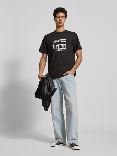 Männermodel trägt Regular Fit T-Shirt mit Logo-Print Modell 'icon' von G-Star Raw aus reiner Baumwolle, schwarze Farbe, Ganzkörperansicht von vorne.