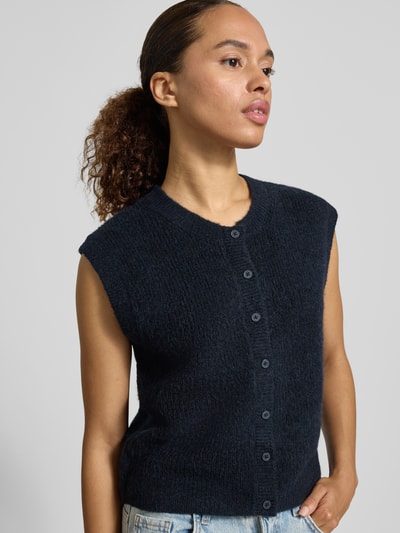 Frauenmodel trägt Regular Fit Strickweste aus Woll-Mix Modell 'LULU' von Selected Femme, dunkelblau, grobe Struktur, Nahaufnahme Oberkörper.
