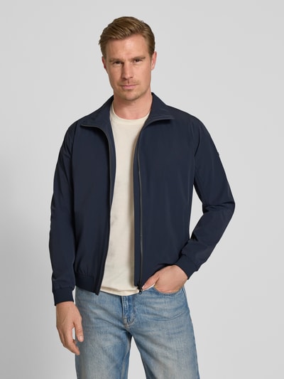 Männermodel trägt Slim Fit Jacke mit Stehkragen Modell 'Apex' von SCANDINAVIAN EDITION im Elastischer-Material-Mix in Dunkelblau, Nahaufnahme Oberkörper. Rückenlänge 65 cm, Schulterbreite 45 cm, Brustweite 42 cm, Ärmellänge 65 cm, Zweiwege-Reißverschluss, elastische Abschlüsse.