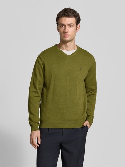Männermodel trägt Strickpullover mit Label-Strickerei von Fynch-Hatton in Grün, V-Ausschnitt, gerader Schnitt, Ganzkörperansicht von vorne.