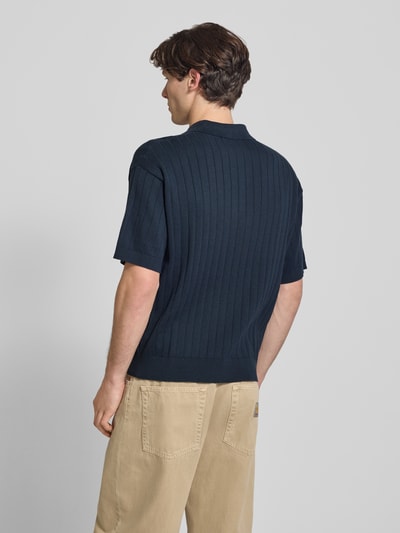 Männermodel trägt Regular Fit Strick-Poloshirt mit Label-Stitching von BLKVIS in Ripp-Optik aus reiner Baumwolle, dunkelblau, Ganzkörperansicht Rückansicht.
