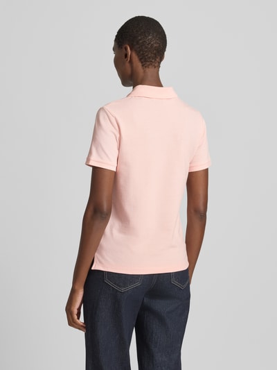 Frauenmodel trägt Poloshirt mit Logo-Stitching und Polokragen von Gant in zartem Rosa, Reine Baumwolle, Regular-Fit, Rückenlänge bei Größe S 57 cm, kurze Knopfleiste, glatte Struktur, Ganzkörperansicht Rückansicht.